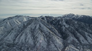 AX125_169 - 5.5K aerial stock footage of slowly orbit Oquirrh Mountains with winter snow in Utah