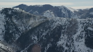AX125_171 - 5.5K aerial stock footage orbit Oquirrh Mountains ridge with snowdrifts in winter, Utah