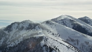 AX125_183E - 5.5K aerial stock footage of snowdrifts on peaks in the Oquirrh Mountains, Utah