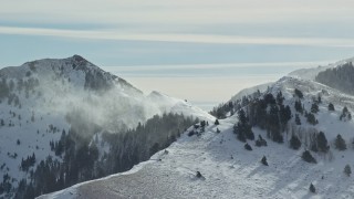 AX125_188E - 5.5K aerial stock footage of a long snowdrift plume in the Oquirrh Mountains, Utah