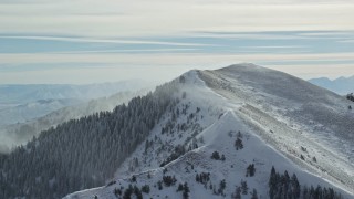 AX125_195E - 5.5K aerial stock footage approach snowy mountain peak with winter snowdrifts, Oquirrh Mountains, Utah