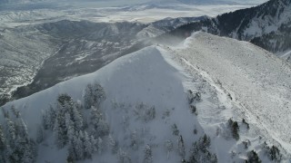 AX125_202 - 5.5K aerial stock footage orbit mountain summit with snowdrifts in wintertime in Oquirrh Mountains, Utah
