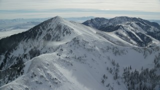 AX125_206 - 5.5K aerial stock footage approach wintery snowdrift off a peak by Lowe Peak, Utah