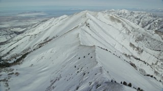 AX125_214E - 5.5K aerial stock footage fly over snowy ridge in Utah's Oquirrh Mountains in wintertime