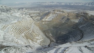 AX125_229 - 5.5K stock footage aerial video orbiting the Bingham Canyon Mine in winter with light snow in Utah