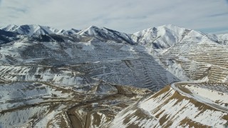 AX125_239E - 5.5K aerial stock footage of the outer rim of the Bingham Canyon Copper Mine and gravel haulers in winter, Utah