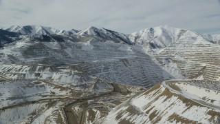 AX125_240 - 5.5K aerial stock footage of orbiting the Bingham Canyon Mine in Utah with winter snow