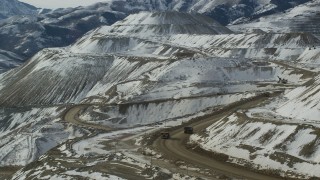AX125_242 - 5.5K aerial stock footage track gravel haulers at the Bingham Canyon Copper Mine with winter snow in Utah
