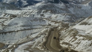 AX125_243 - 5.5K aerial stock footage orbit Bingham Canyon Mine with gravel haulers and light snow, Utah