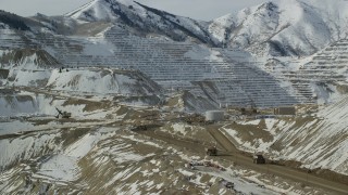 AX125_244 - 5.5K aerial stock footage orbit gravel haulers at the giant Bingham Canyon Mine with winter snow, Utah