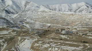 AX125_245 - 5.5K aerial stock footage orbit the Bingham Canyon Mine and gravel haulers on a dirt road in winter, Utah