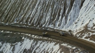 AX125_248 - 5.5K aerial stock footage of four gravel haulers at the Bingham Canyon Copper Mine with winter snow in Utah