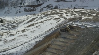 AX125_250 - 5.5K aerial stock footage of hauler dumping gravel at the Bingham Canyon Mine in winter, Utah
