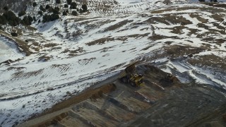AX125_250E - 5.5K aerial stock footage of hauler dumping gravel at the Bingham Canyon Mine in winter, Utah