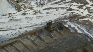 AX125_252 - 5.5K aerial stock footage of gravel hauler dumping dirt and rocks at Bingham Canyon Mine, Utah, in winter