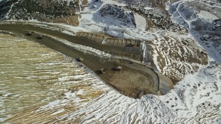 AX125_253 - 5.5K aerial stock footage of gravel haulers moving on dirt road at Bingham Canyon Mine with snow, Utah