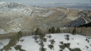 AX125_262 - 5.5K stock footage aerial video fly over snowy mountain ridge to reveal enormous open pit copper mine with winter snow, Utah