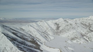 AX125_265 - 5.5K aerial stock footage of passing by a snow-covered mountain ridge in wintertime, Oquirrh Mountains, Utah