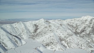 AX125_265E - 5.5K aerial stock footage of passing by a snow-covered mountain ridge in wintertime, Oquirrh Mountains, Utah