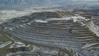 AX125_268 - 5.5K aerial stock footage of orbiting the side of the Bingham Canyon Mine with light winter snow, Utah
