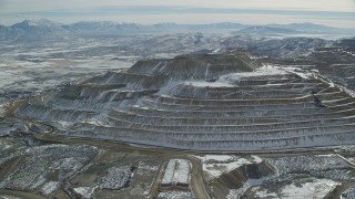 AX125_270 - 5.5K aerial stock footage of tiered hill with winter snow at the Bingham Canyon Mine, Utah