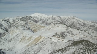AX125_271 - 5.5K aerial stock footage orbit an open pit mine with winter snow in the Oquirrh Mountains, Utah