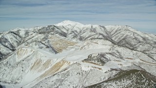 AX125_271E - 5.5K aerial stock footage of an open pit mine with winter snow in the Oquirrh Mountains, Utah