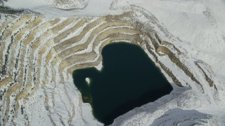 AX125_276 - 5.5K aerial stock footage tilt to bird's eye view of a water-filled open pit mine with winter snow, Oquirrh Mountains, Utah