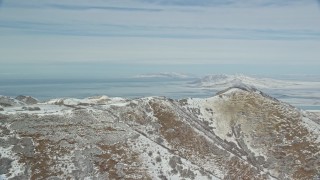 AX125_286 - 5.5K aerial stock footage of Great Salt Lake seen from a snowy ridge in the Oquirrh Mountains, Utah