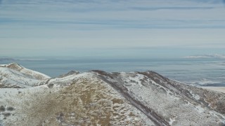 AX125_287E - 5.5K aerial stock footage of snowy mountain ridge with view of Great Salt Lake in winter, Utah