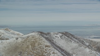 AX125_288 - 5.5K aerial stock footage of Great Salt Lake seen while orbiting snowy mountain ridge in winter, Utah