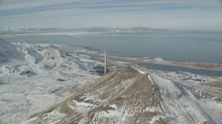 AX125_294 - 5.5K aerial stock footage approach Kennecott Smokestack and snowy mountain to reveal factory in winter in Magna, Utah
