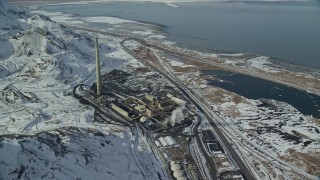 AX125_295E - 5.5K aerial stock footage of Kennecott Smokestack and factory buildings with winter snow in Magna, Utah