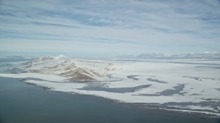 AX125_306E - 5.5K aerial stock footage of panning across snow mountains on the shore of the Great Salt Lake in Utah