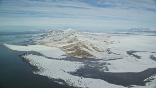 AX125_311E - 5.5K aerial stock footage approach snowy mountains on the shore of Antelope Island, Utah