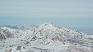 AX125_315 - 5.5K aerial stock footage of orbiting a snowy Antelope Island mountain peak in winter, Utah