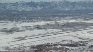 AX125_322 - 5.5K stock footage aerial video of slow approach to Salt Lake City International Airport with winter snow, Utah