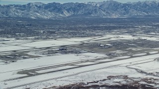 AX125_322E - 5.5K aerial stock footage of slow approach to Salt Lake City International Airport with winter snow, Utah