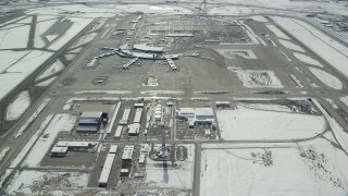 AX125_330 - 5.5K aerial stock footage of control tower and terminals at Salt Lake City International Airport with winter snow, Utah