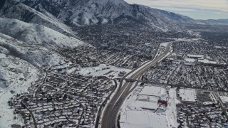 AX126_067 - 5.5K aerial stock footage pan across Interstate 215 through suburbs in Salt Lake City with winter snow, Utah