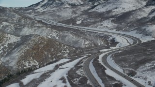 AX126_079 - 5.5K aerial stock footage approach bend in freeway through snowy mountain pass in Utah's Wasatch Range