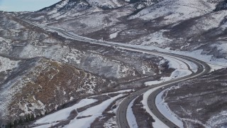 AX126_079E - 5.5K aerial stock footage approach bend in freeway through snowy mountain pass in Utah's Wasatch Range