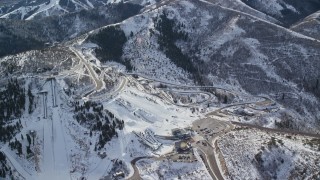 AX126_098 - 5.5K aerial stock footage orbit the tracks and ski jumps at Utah Olympic Park with winter snow, Park City