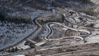 AX126_102 - 5.5K aerial stock footage orbit the winding luge and bobsled track at Utah Olympic Park with winter snow, Park City