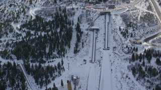 AX126_107 - 5.5K aerial stock footage orbiting two ski jumps with winter snow at Utah Olympic Park, Park City