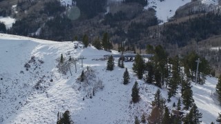 AX126_121E - 5.5K aerial stock footage orbit gondolas at the summit of a snowy mountain in winter, Park City, Utah