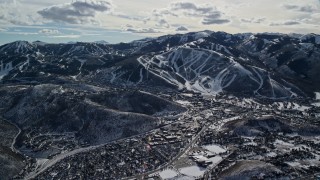 AX126_152E - 5.5K aerial stock footage of reverse view of Park City Mountain Resort slopes beside the town in winter, Utah