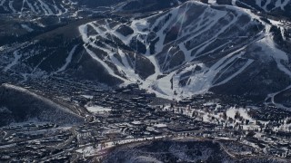 AX126_154E - 5.5K aerial stock footage of snowy ski runs beside a small town in winter, Park City, Utah