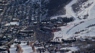 AX126_161E - 5.5K aerial stock footage of hotels below ski runs at a winter resort in Utah's Park City