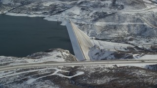 AX126_182 - 5.5K aerial stock footage orbiting Jordanelle Dam with winter snow in Heber City, Utah